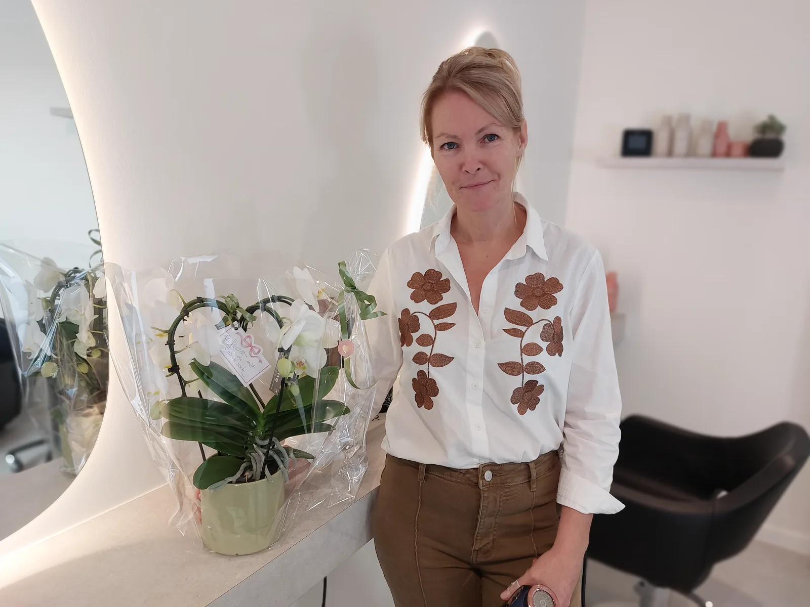 Sofie in het salon, naast een witte orchidee bij de spiegel